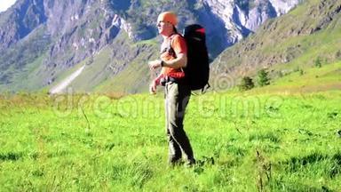 徒步旅行者带着背包在绿色的山地草地上行走。 夏季运动和娱乐理念。